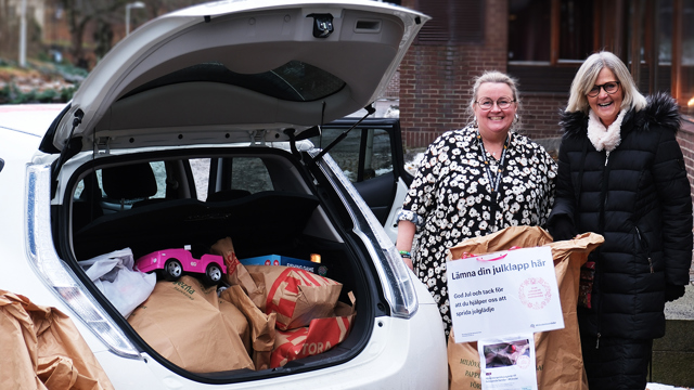 två kvinnor står bredvid en bil med öppet bagage fylld med julklappar för insamlingen Julgåvan utanför församlingshemmet i Mölndal 